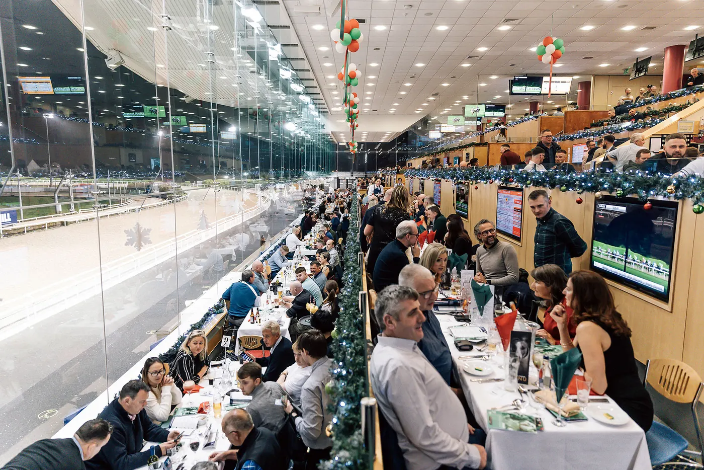 A long table of guests at a Christmas party in The View, garlands along the glass.